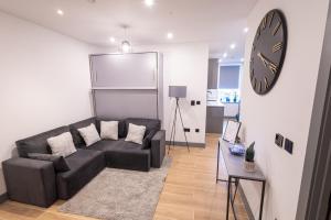 a living room with a couch and a clock on the wall at Chic 2King BD Apt London with Ensuite & Pull Out Bed in Finchley