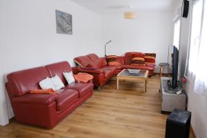 a living room with red leather couches and a tv at Evasion Marine, Cozy home in Criel-sur-Mer