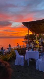 a group of people sitting at tables watching the sunset at SiQUIJOR SEA SHORE HOUSE in Siquijor