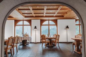 a dining room with tables and chairs and windows at Hotel Maloja Kulm in Maloja