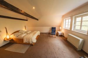 ein Schlafzimmer mit einem Bett und einem Stuhl und einem Fenster in der Unterkunft Romantische, alte Wassermühle in Rieste
