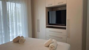 a bedroom with a tv and towels on a bed at Milto's Apartment in Limenaria