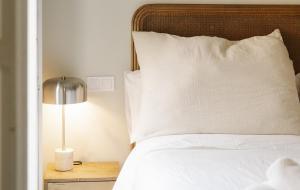 a bed with a pillow and a lamp on a night stand at Cream Boutique Málaga in Málaga