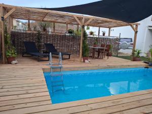 ein Pool mit einer Holzterrasse und einem schwarzen Sonnenschirm in der Unterkunft Guesthouse Fuik in Willemstad