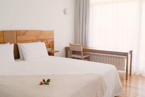 a bedroom with a white bed with a flower on it at Hotel A Miranda in Feás