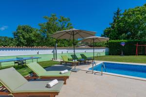a pool with lounge chairs and umbrellas next to a swimming pool at Villa Dajana, a cozy pet friendly Villa minutes from the beach in Juršići