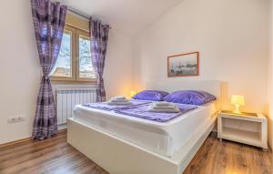 Un dormitorio con una cama con almohadas moradas y una ventana en Stunning Home In Medulin, en Medulin