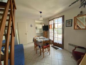 a kitchen and dining room with a table and a staircase at Maison Normandie 19 in Fort-Mahon-Plage +5 photos