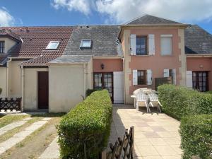 a house with two chairs and a table in front of it at Maison Normandie 19 in Fort-Mahon-Plage