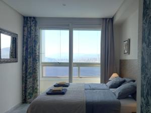 Un dormitorio con una cama y una ventana grande. en Benidorm Gemelos penthouse with private pool, en Benidorm 32 fotos más