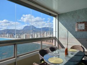 una mesa y sillas en una habitación con vistas a la ciudad en Benidorm Gemelos penthouse with private pool, en Benidorm