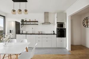 eine Küche mit weißen Schränken und einem Tisch und Stühlen in der Unterkunft Magnifique Chambre dans une collocation design in Rouen