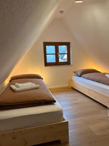 two beds in a attic bedroom with a window at Ferienhaus Schmuckstück in Schiltach