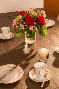 eine Vase mit Blumen auf einem Tisch mit Teller und Tassen in der Unterkunft Ferienwohnung in Otterndorf in Otterndorf