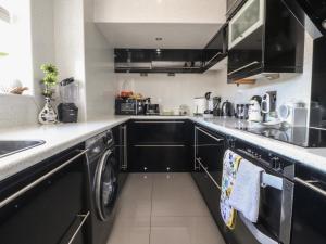 a kitchen with black cabinets and a washer and dryer at 17 Alexandra Court in Skipton