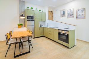 une cuisine avec des armoires vertes et une table avec des chaises dans l'établissement CARTAGENAFLATS - San Diego Suites, à Carthagène