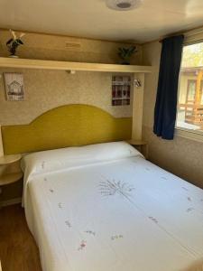 a bedroom with a white bed with a yellow headboard at Bungalow 477 Colibrì in Ameglia