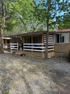a log cabin with a porch and a tree at Bungalow 477 Colibrì in Ameglia
