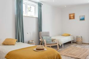 a room with two beds and a chair and a window at CoWorking and CoLiving Villa in Sagres