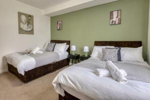 a bedroom with two beds and two tables with lamps at Comfortable 3 Bedroom Home with Parking Pet Friendly Sleeps 8 in Knowsthorpe