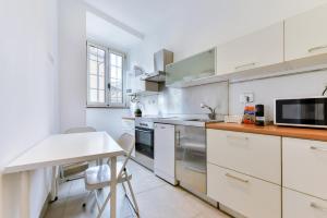 Una cocina con gabinetes blancos y una mesa y un microondas. en Lavinia's Apartment at Colosseo, en Roma