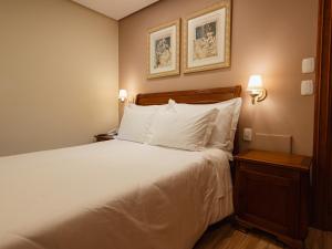 a bedroom with a bed with white sheets and pillows at Kurotel Centro Contemporâneo de Saúde e Bem Estar in Gramado