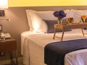 a bed with a table with flowers on it at Kurotel Centro Contemporâneo de Saúde e Bem Estar in Gramado