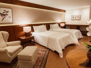 a hotel room with two beds and a chair at Kurotel Centro Contemporâneo de Saúde e Bem Estar in Gramado