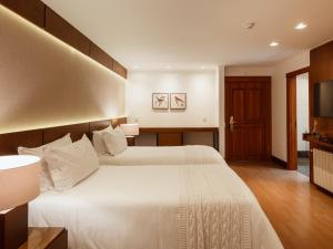 a hotel room with two beds and a television at Kurotel Centro Contemporâneo de Saúde e Bem Estar in Gramado