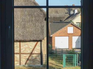 Una vista de ventana de un edificio de ladrillo con techo de paja en Körkhus, en Dorf Körkwitz 6 fotos más