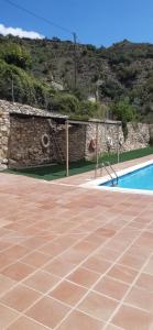 a swimming pool next to a stone wall next to aphalt at Casa Potenta in Llimiana