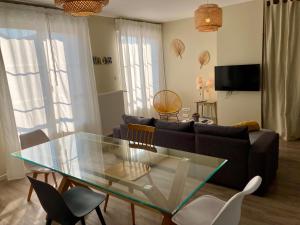 a living room with a glass table and a couch at La maison Virginie appartements climatisés de 1 à 5 pers cosy central parking gratuit linge fibre proximité port lac canal piscine in Montargis