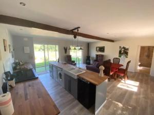 a kitchen and living room with a couch and a table at La Bergerie Luxury cottage and pool on eco-friendly micro-farm in Duravel