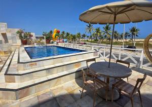a table with an umbrella next to a swimming pool at Jatobá Praia Hotel in Aracaju