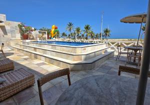 a patio with a swimming pool with tables and chairs at Jatobá Praia Hotel in Aracaju