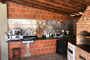 a kitchen with a brick wall with a counter top at Casa com piscina in Gravatá