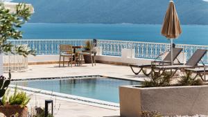 a swimming pool with chairs and an umbrella and the ocean at Casa Caria Suites in Bodrum City +20 photos