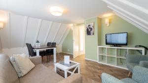 a living room with a couch and a tv and a table at Les Maisons Domburg in Domburg