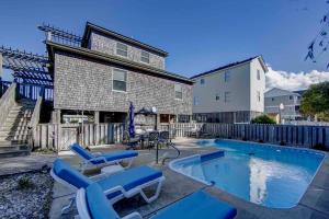 a house with a swimming pool and blue chairs at Waz Up Beaches in Sanderling