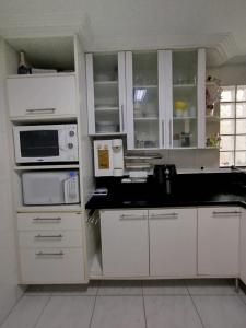 a kitchen with white cabinets and white appliances at Casa em Vitória - Próximo a Praia in Vitória