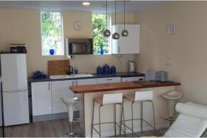a kitchen with white cabinets and a counter with stools at Bali Hi Cliff Cottage-Sleeps 2-Hot Tub-5MinBeach in Sheerness