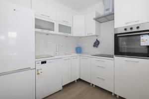 a white kitchen with white cabinets and a sink at Apartman MORE Živogošće in Živogošće +13 photos
