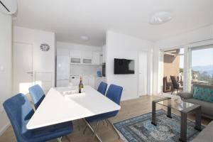 a dining room with a white table and blue chairs at Apartman MORE Živogošće in Živogošće