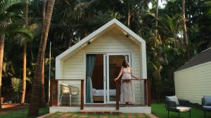 a woman standing on a porch of a tiny house at Sea Breeze, Guhagar in Guhagar