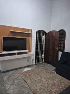 a living room with a television and a door at Casa Relaxemar in Caraguatatuba