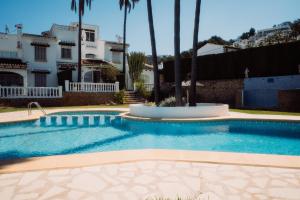 a swimming pool in front of a house with palm trees at Casa Bianca 2 in Teulada