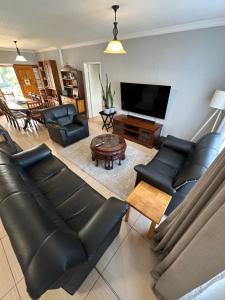 a living room with black leather furniture and a flat screen tv at DuyneGuestHouse in Cape Town