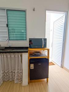 a room with a table with a television and a window at Villa Makai Flats Maresias in Maresias