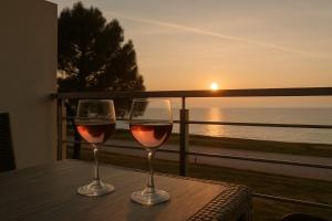 two glasses of wine sitting on a table with the sunset at Alkyon Apartments Studios in Platanitis +20 photos
