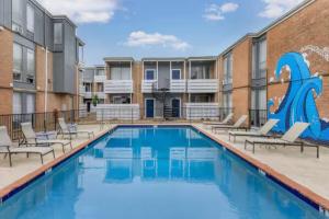 une piscine avec des chaises et un bâtiment dans l'établissement Inviting Houston Space Near Kemah and Space Center, à Houston